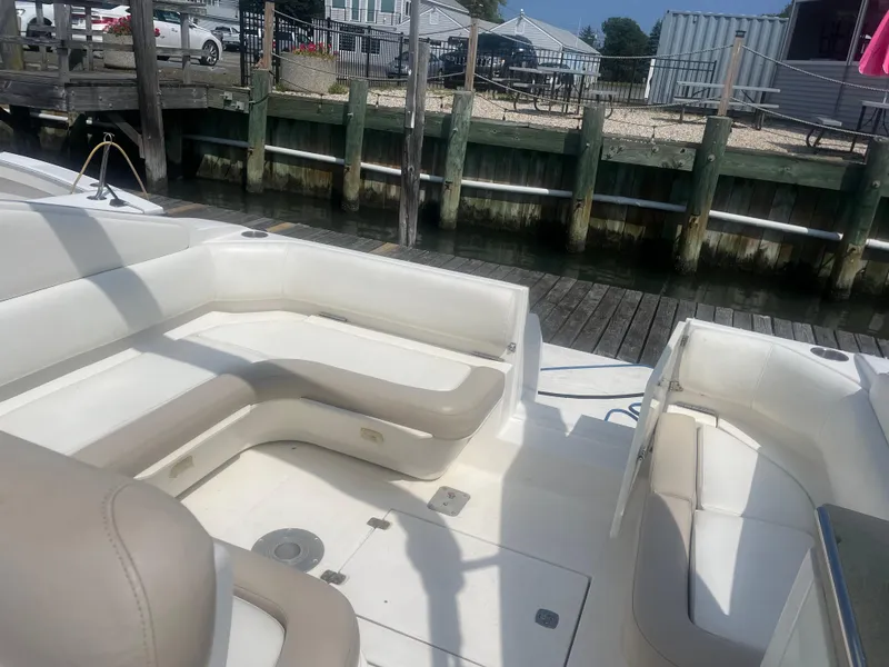 Slide: The Image of 2003 Regal 3260 Commodore boat interior with white seating at a dock. - 2