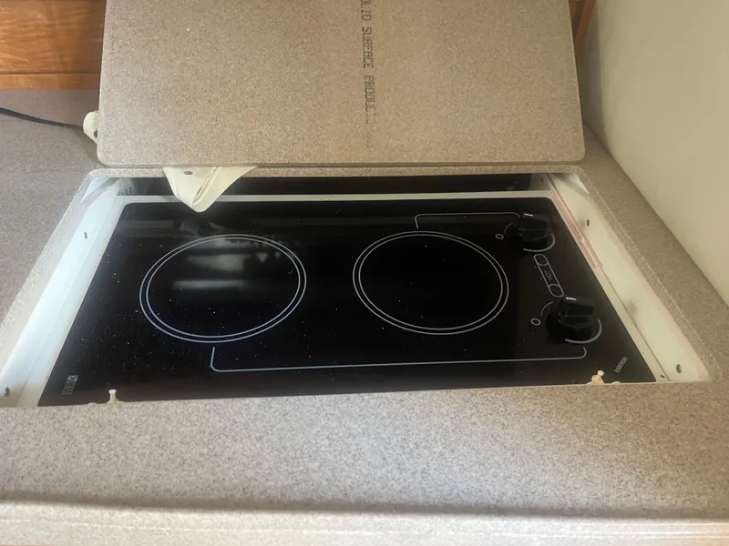 Slide: The Image of Electric stove in 2003 Regal 3260 Commodore boat kitchen, featuring two burners and a cover. - 5