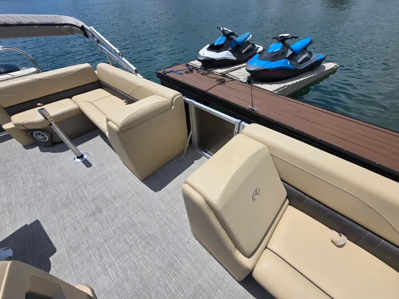 Slide: The Image of 2020 Avalon LSZ Cruise II boat interior with beige seating, docked near jet skis. - 7