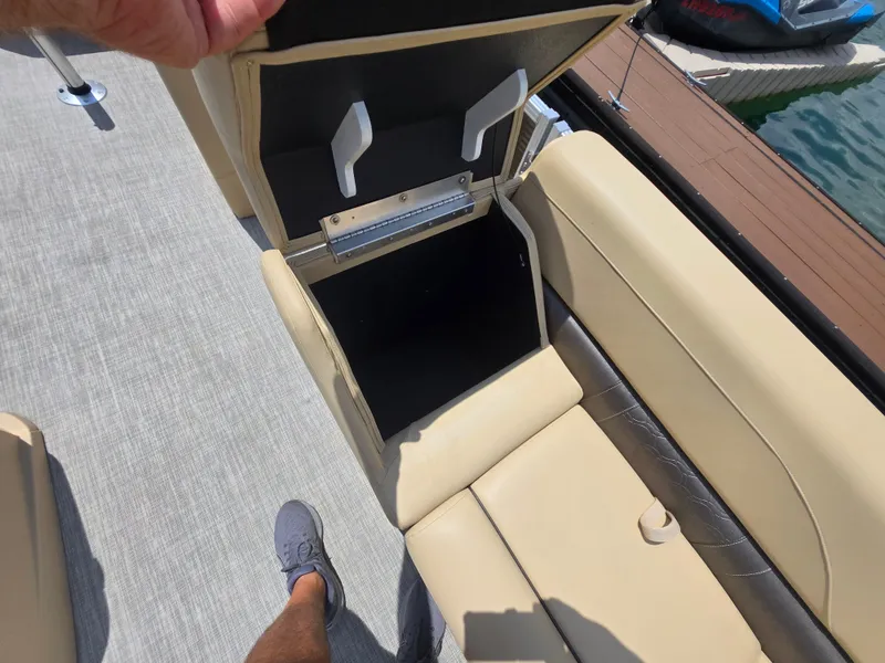 Slide: The Image of Open storage compartment on Avalon LSZ Cruise II 2020 boat, beige seating, dock in background. - 8