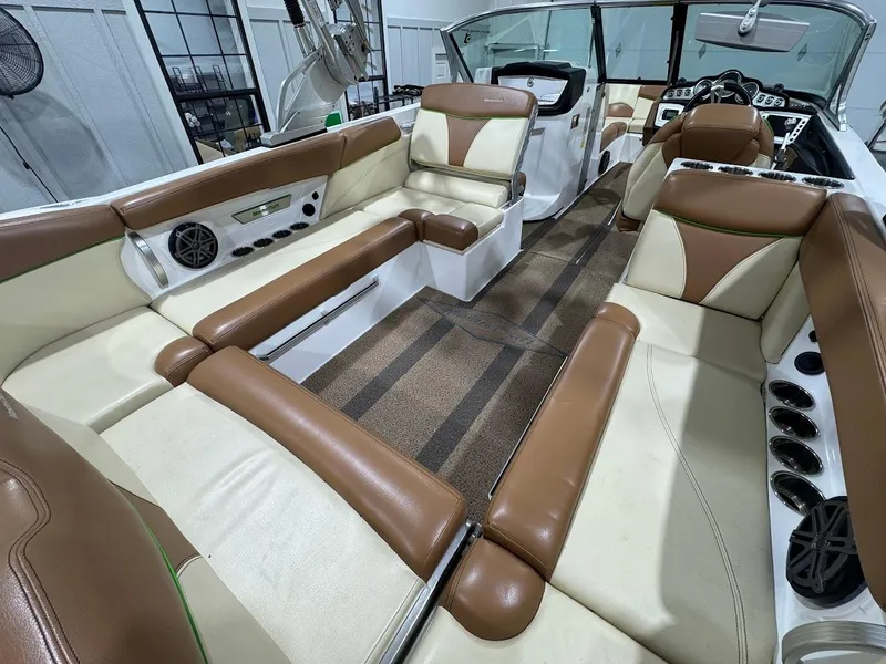 Slide: The Image of 2016 MasterCraft X26 boat interior with brown and cream seating, cup holders, and speakers. - 13