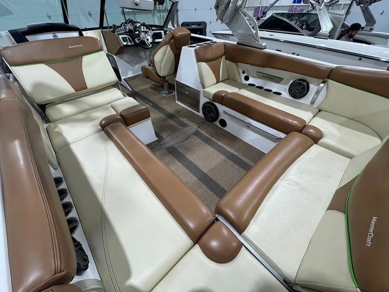 Slide: The Image of 2016 MasterCraft X26 boat interior with brown and cream seating, featuring modern dashboard and speakers. - 14