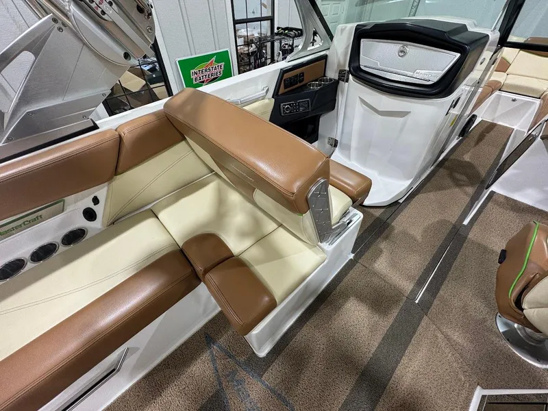 Slide: The Image of 2016 MasterCraft X26 interior with brown and cream seating, modern dashboard, and cup holders. - 16