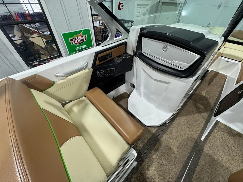 Slide: The Image of 2016 MasterCraft X26 interior with tan and cream seating, modern dashboard, and cup holder. - 17