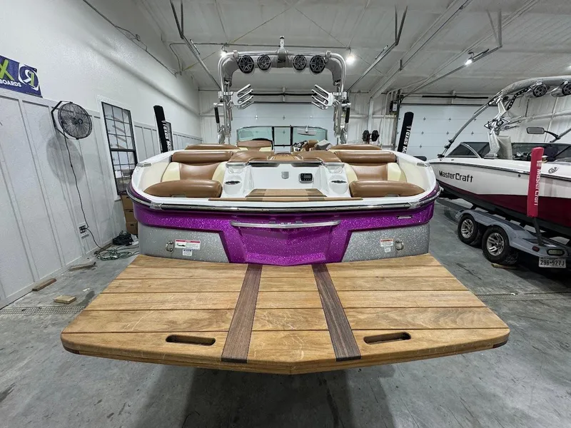 Slide: The Image of 2016 MasterCraft X26 boat with purple accents and wooden deck in a showroom. - 3