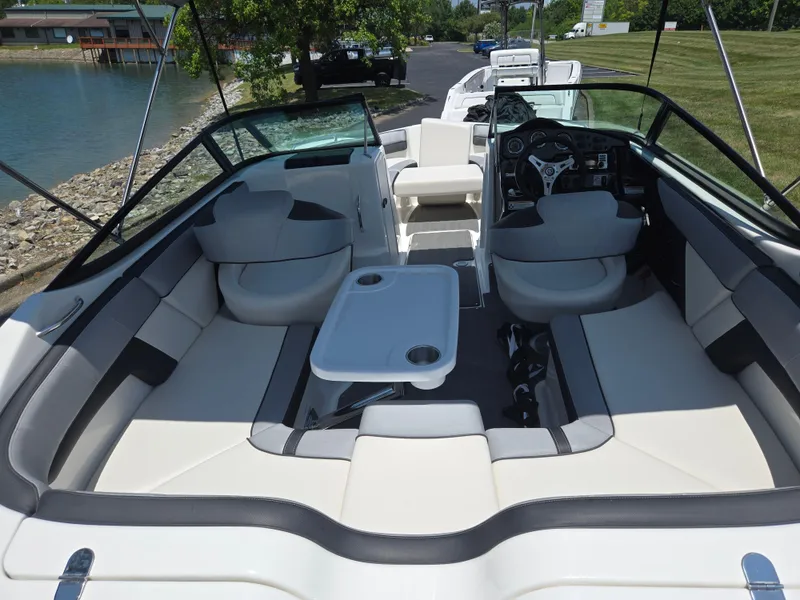 Slide: The Image of 2013 Yamaha Boats 212SS interior with seating and table, docked by a lake. - 10