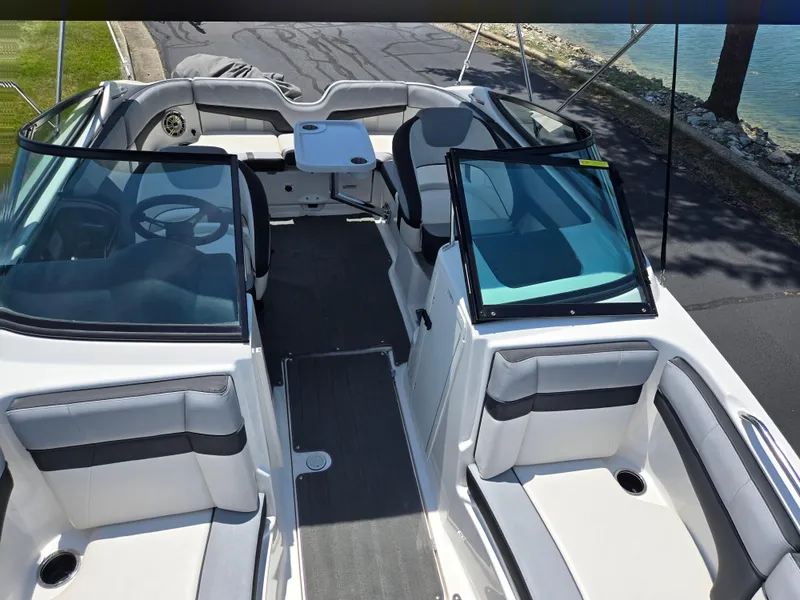 Slide: The Image of 2013 Yamaha Boats 212SS interior with seating and steering wheel, docked by a lake. - 19
