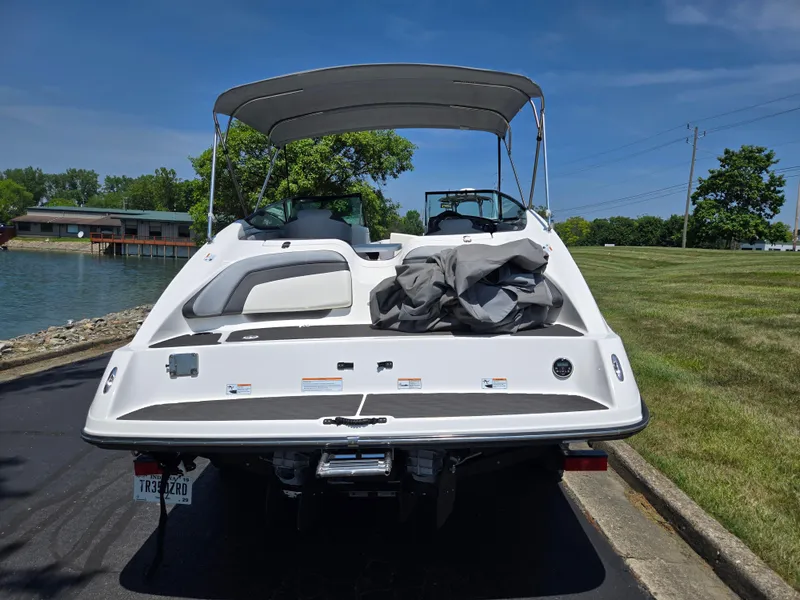 Slide: The Image of 2013 Yamaha Boats 212SS docked near a lake, showcasing its sleek design and canopy. - 2