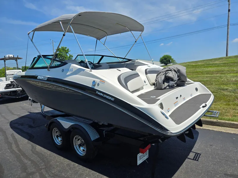 Slide: The Image of 2013 Yamaha Boats 212SS on trailer, featuring twin engines and a canopy, parked outdoors. - 3
