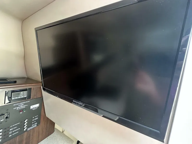 Slide: The Image of Flat-screen TV and control panel inside 2017 Regal 26 Express boat cabin. - 49