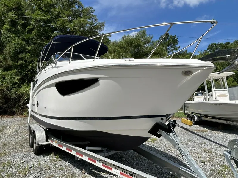 Slide: The Image of 2017 Regal 26 Express boat on trailer, parked outdoors with trees in background. - 7