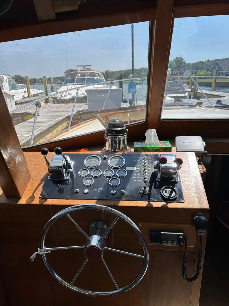 Slide: The Image of 1977 Egg Harbor 33 Sedan helm with gauges, steering wheel, and controls in a marina setting. - 14