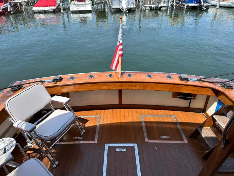 Slide: The Image of 1977 Egg Harbor 33 Sedan boat deck with chairs and American flag, docked at marina. - 28