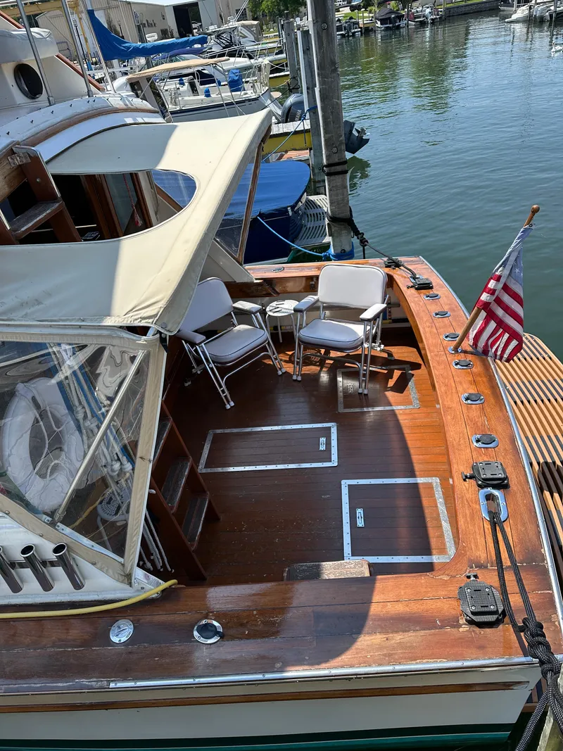 Slide: The Image of 1977 Egg Harbor 33 Sedan boat with wooden deck, chairs, and American flag at marina. - 8