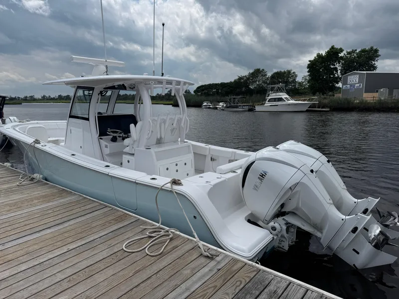 Slide: The Image of 2024 Sportsman Open 302 Center Console boat docked by a wooden pier under cloudy skies. - 4