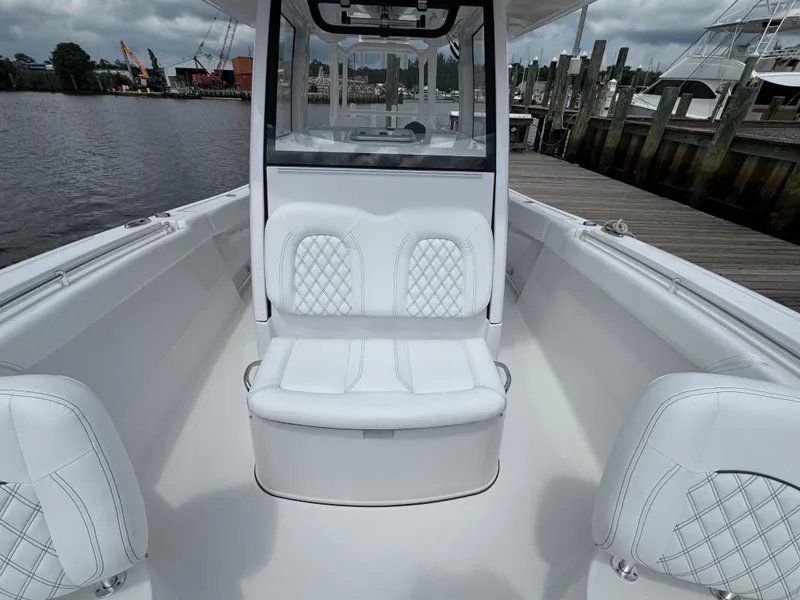 Slide: The Image of 2024 Sportsman Open 302 Center Console boat with white seating, docked by the water. - 9