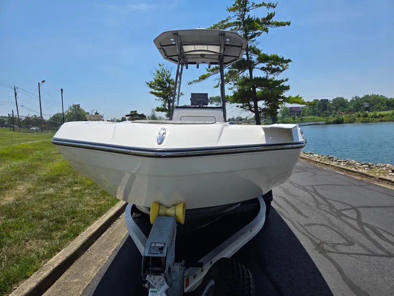 Slide: The Image of 2018 Yamaha Boats 210 FSH Sport on trailer by a lakeside road. - 6