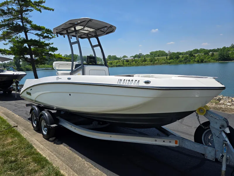 Slide: The Image of 2018 Yamaha Boats 210 FSH Sport on trailer by a lake. - 8