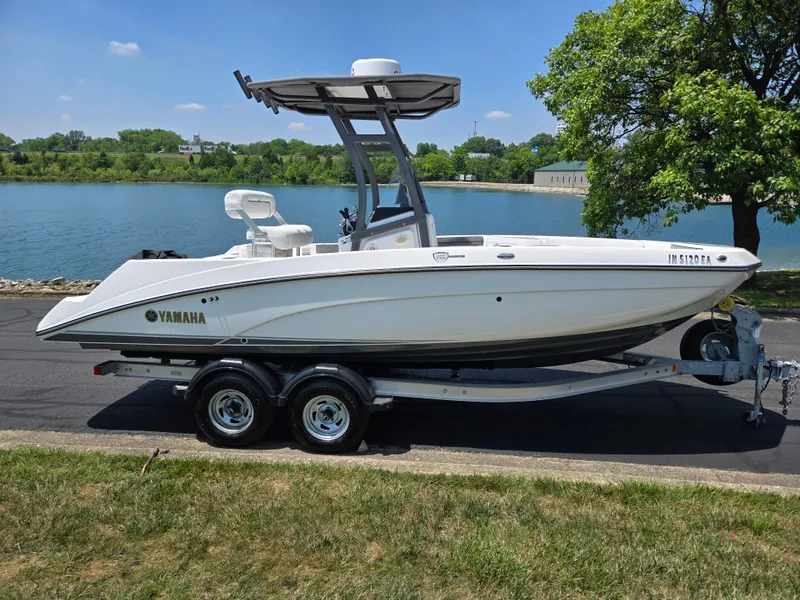 Slide: The Image of 2018 Yamaha Boats 210 FSH Sport on trailer by a lake, sunny day. - 9
