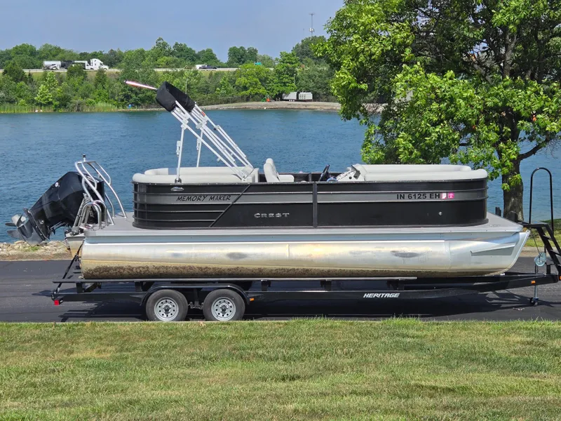 Slide: The Image of 2021 Crest Classic LX 220 SLC pontoon boat on trailer by a lake. - 0