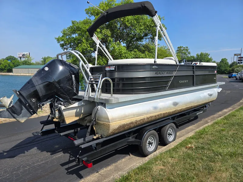 Slide: The Image of 2021 Crest Classic LX 220 SLC pontoon boat on trailer, parked near water. - 1