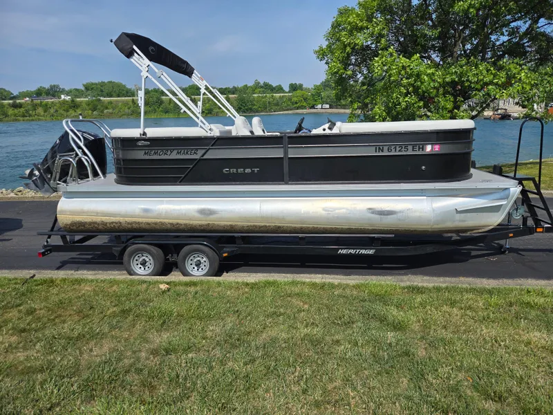 Slide: The Image of 2021 Crest Classic LX 220 SLC pontoon boat on trailer by a riverbank. - 10