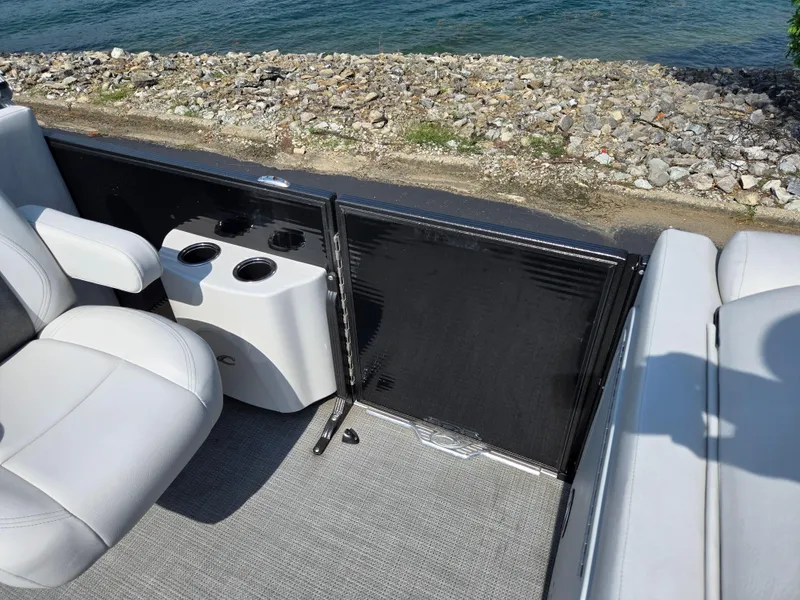 Slide: The Image of 2021 Crest Classic LX 220 SLC boat interior with seating and cup holders by the water. - 14