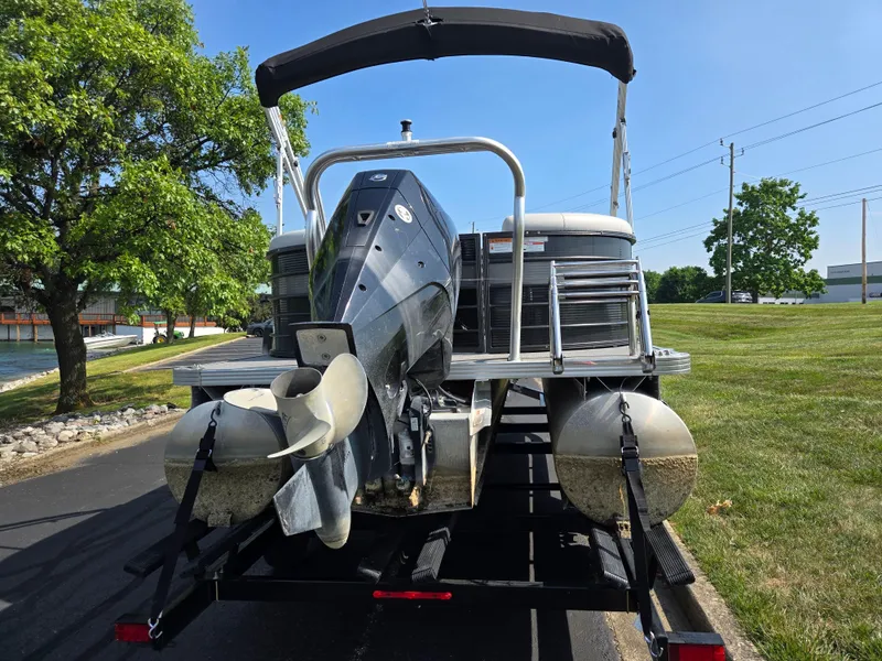 Slide: The Image of 2021 Crest Classic LX 220 SLC pontoon boat on trailer, parked near a grassy area. - 2