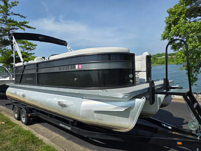 Slide: The Image of 2021 Crest Classic LX 220 SLC pontoon boat on trailer by a lake. - 9