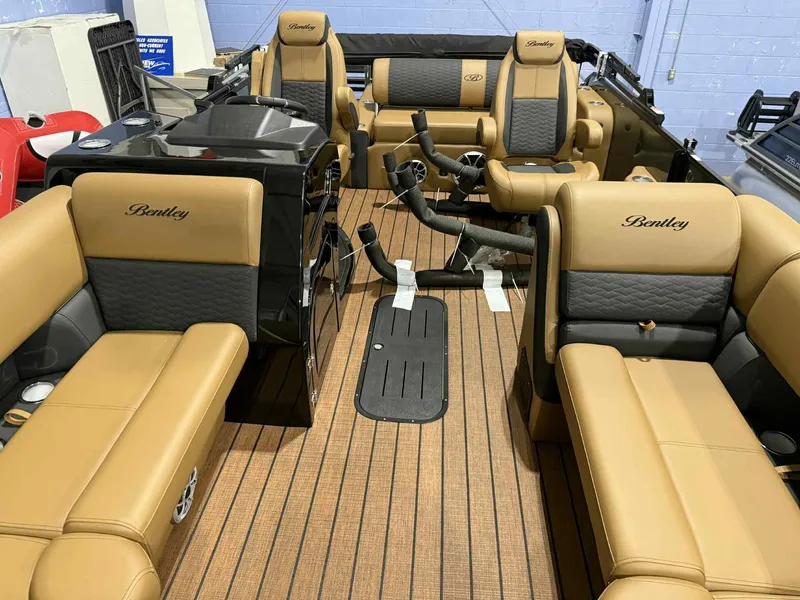 Slide: The Image of 2026 Bentley Pontoons Elite 223 interior with tan and black seating, dual captain chairs, and wood flooring. - 5