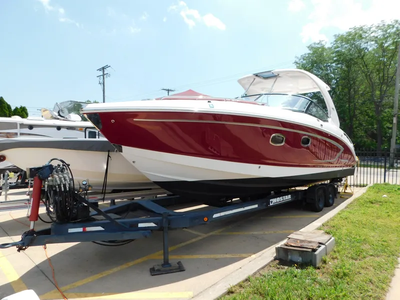 Slide: The Image of 2013 Chaparral 327 SSX boat on trailer, red and white exterior, parked outdoors. - 2