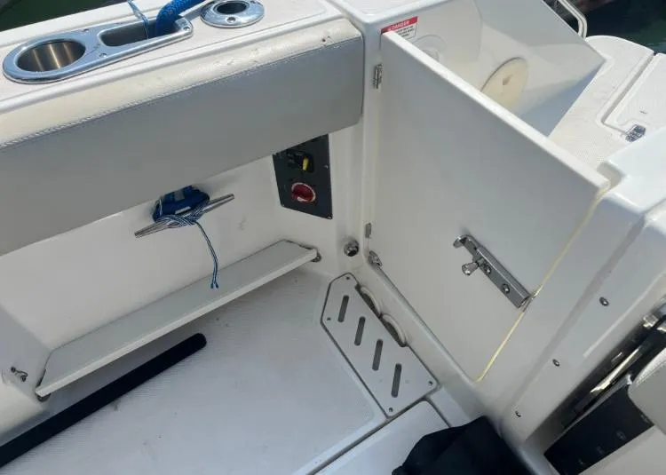 Slide: The Image of 2023 Boston Whaler 240 Vantage boat interior with open storage compartment and cup holder. - 13