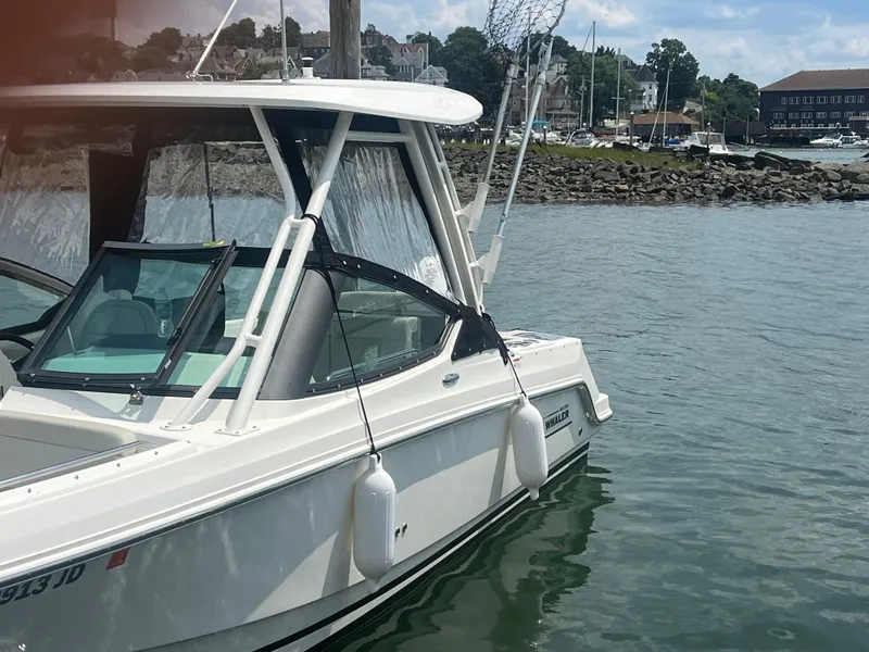 Slide: The Image of 2023 Boston Whaler 240 Vantage boat docked in a scenic harbor. - 2