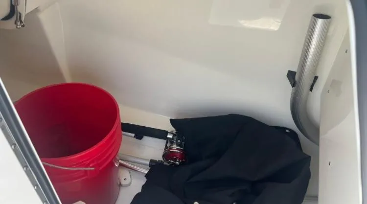 Slide: The Image of Storage compartment of 2023 Boston Whaler 240 Vantage with red bucket and fishing gear. - 24