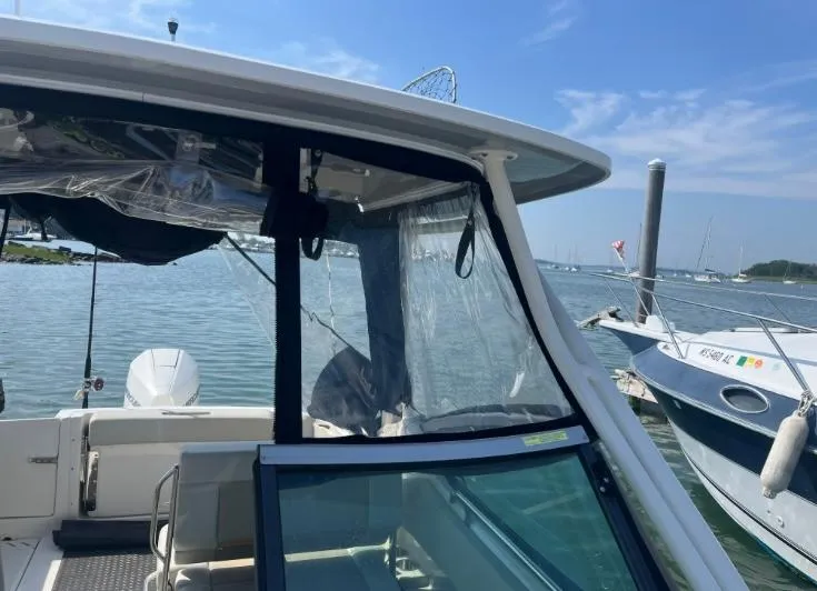 Slide: The Image of 2023 Boston Whaler 240 Vantage boat docked in a marina under a clear blue sky. - 8