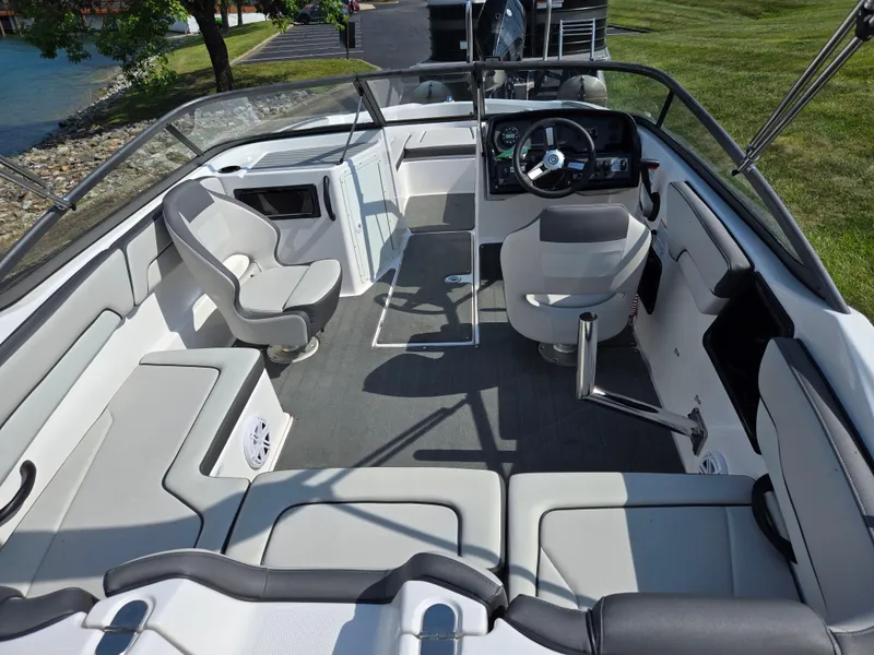 Slide: The Image of 2021 Yamaha Boats SX190 interior with seating and steering wheel, docked near grassy area. - 10