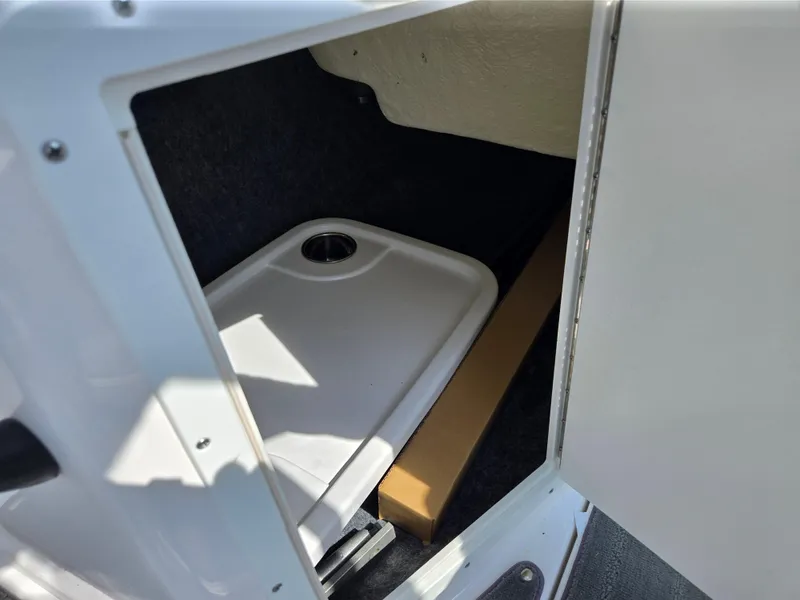 Slide: The Image of 2021 Yamaha SX190 boat storage compartment with white tray and cup holder. - 15
