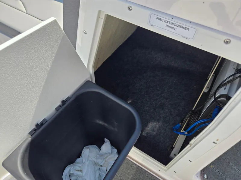 Slide: The Image of 2021 Yamaha SX190 boat storage compartment with fire extinguisher and trash bin. - 16