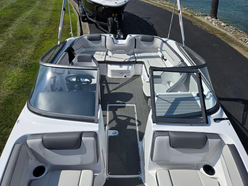 Slide: The Image of 2021 Yamaha Boats SX190 interior with seating and steering wheel, docked near grass and water. - 19