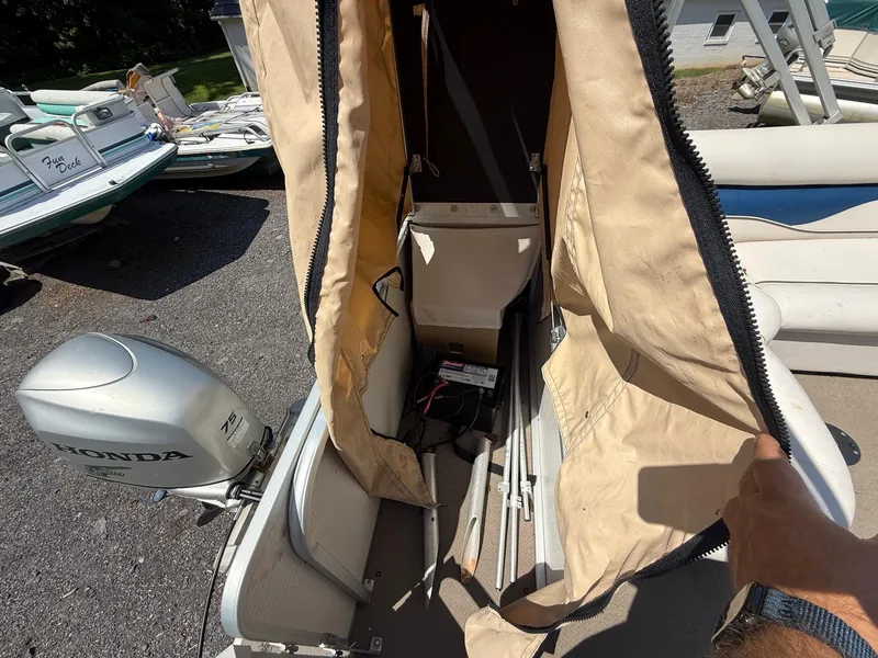 Slide: The Image of 2009 Premier 200 SunSpree boat with Honda 75 engine, open storage compartment, and visible battery. - 12