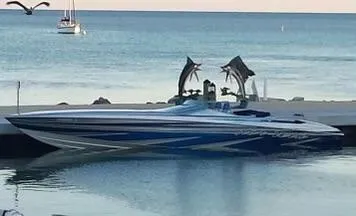 Slide: The Image of 2013 Nor-Tech 477 SPX Vee Bottom boat docked by the sea with dolphin sculptures. - 3