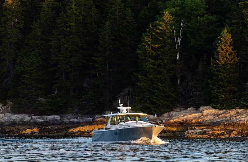 Slide: The Image of 2026 Sabre 43 Salon Express cruising near forested shoreline. - 5