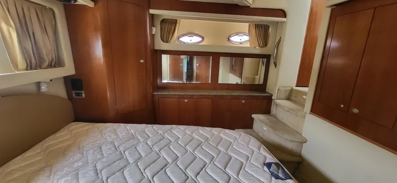 Slide: The Image of Interior of 2005 Sea Ray 390 Motor Yacht with bed, wooden cabinets, and porthole windows. - 16
