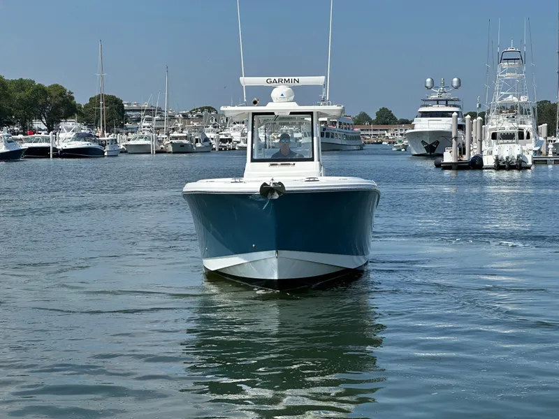 Slide: The Image of 2023 Edgewater 285CC boat navigating a marina, surrounded by yachts and calm water. - 11