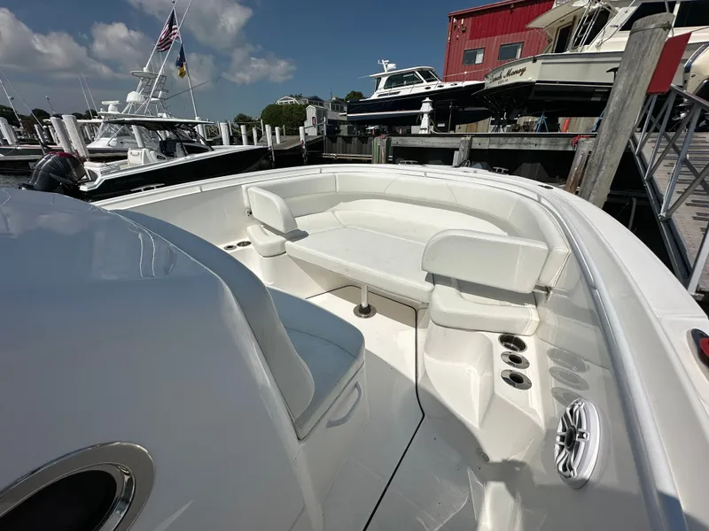 Slide: The Image of 2023 Edgewater 285CC boat interior with seating and table at a marina. - 12