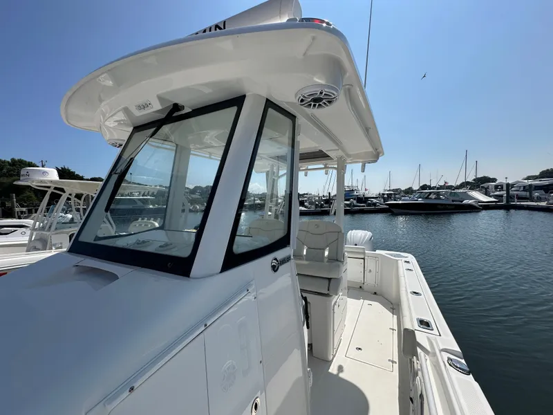 Slide: The Image of 2023 Edgewater 285CC boat docked at marina under clear blue sky. - 13