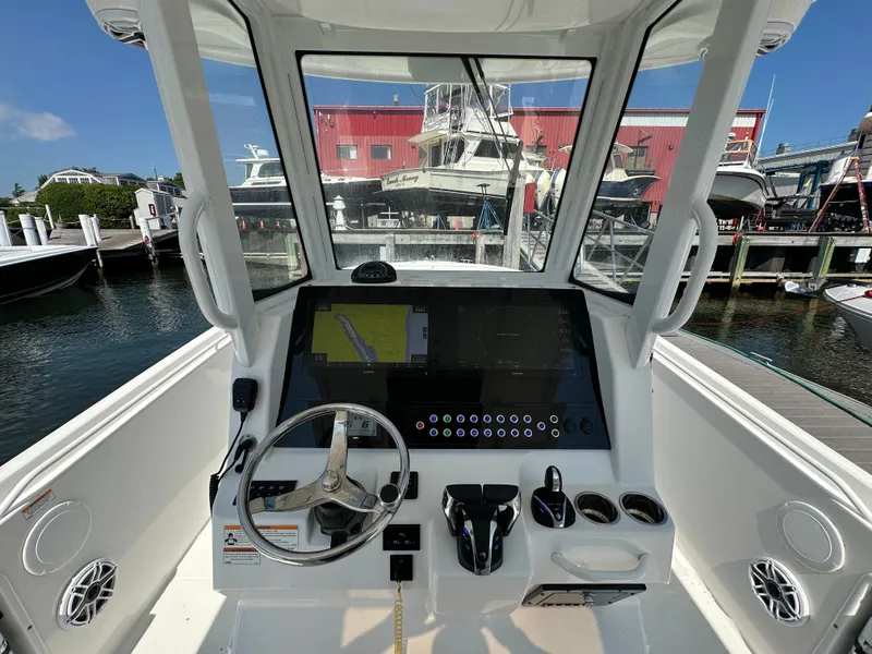 Slide: The Image of 2023 Edgewater 285CC boat cockpit with modern navigation system and controls at a marina. - 15