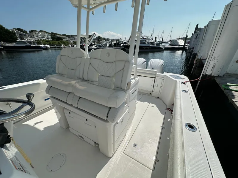 Slide: The Image of 2023 Edgewater 285CC boat interior with white seating, docked in a marina. - 17