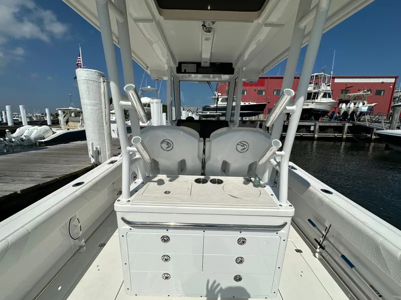 Slide: The Image of 2023 Edgewater 285CC boat interior at marina, featuring fishing rod holders and storage compartments. - 18