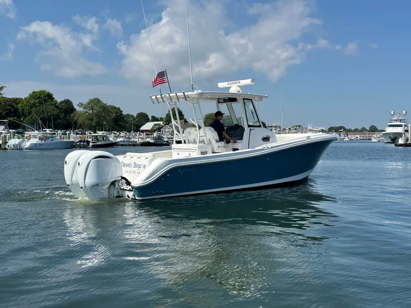 Slide: The Image of 2023 Edgewater 285CC boat cruising on a sunny day in a marina. - 2